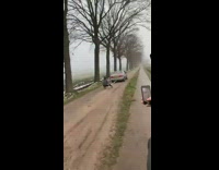 Car pulls guy on sleigh across dirt