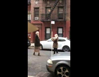 Two women take pictures walking down street