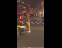Naked man stands in traffic at night