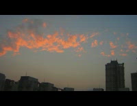 Orange clouds splattered over buildings sunset sky