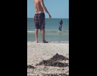 Guy blue shorts friend spray water beach