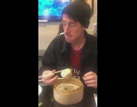 Guy bites into dumpling with soup, soup squirts out and spills all over table