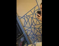 Girl paints wall tape triangles