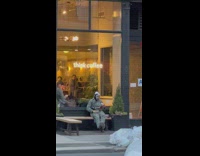 Man Sits In Front of Café and Drinks Tea