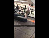 Balding guy in gym practicing how to stand up on surfboard