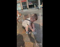 Baby boy plays at the fountain gets splashed