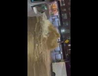 dirty brown flood water rushes out of street floor