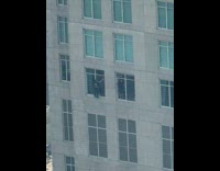 Men cleans building window without safety gear