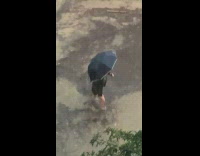 Woman walks flooded street during heavy storm