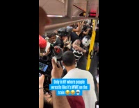 Crowd inside subway train watching men wrestle 