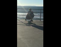 man balancing on cylinder on pier looking at ocean