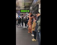 Person wear inflatable dinosaur costume in subway