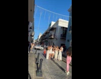Five women white dress dances middle street