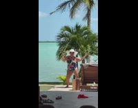 Old woman in one piece bathing suit outdoors by pool dance to music 
