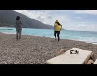 Woman yellow shirt bucket hat runs beach rock 