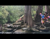 Green bikini girl kneels poses rock lake
