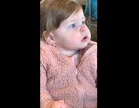 Baby in pink furry jacket making grunting faces at lunch 
