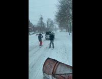 Car dragging two guys wearing snowboards and skis on the road