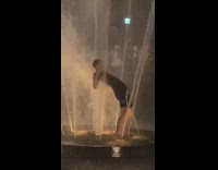 Guy bends back over water fountain 