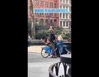 Guy with bicycle balances cup on head 