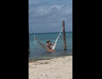 Guy shiny hat swing hammock beach selfie