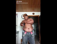 Shirtless guy sticks objects under fat rolls 