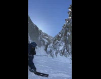 Guy skis does steep mountain between rocks and falls down slope