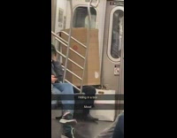 Person hiding inside cardboard box while sitting on subway