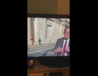 Woman in red top poses behind the news reporter on TV Part 5