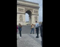 Woman with brown jacket poses in front of the arc