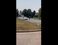 Woman dances with hula-hoop front of car