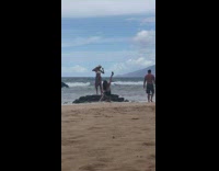 Woman in tie dye loses hat while modeling on beach 