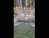 Guy does backbend being carried by fountain water 
