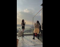 Woman in black dress poses on rooftop