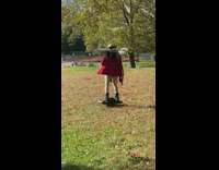 Person wearing wings rides onewheel across grass 