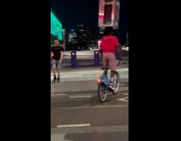 Man rides bike balances Microwave on head