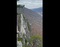 Man jumps on top of the rock and parachute glide down