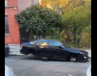 Parked black car with stolen wheels street