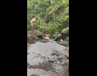Woman in bikini leans on the river while two men takes picture