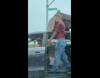 Guy holds brown couch grey minivan roof 