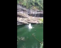 Person jumps off cliff into water 