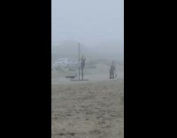 Woman black dress stilt pole dance beach