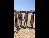 Four guys shotgun beers at the beach, blue and American flag swimming trunks