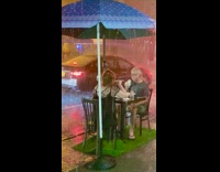 Couple restaurant table blue umbrella rain sidewalk 