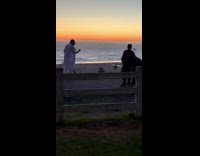Man white robe rap beach fence sunset