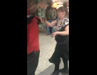 Man plays drums using a white chair, couple dances to music in subway station