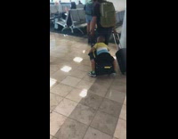 Little boy lays on rolling luggage airport 