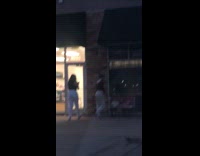 Two women tiktok dance in front of the store
