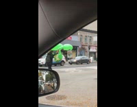 Woman carries giant inflatable alien while crossing street 