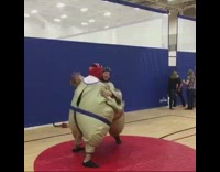 Two guys sumo costumes wrestling red circle floor gym